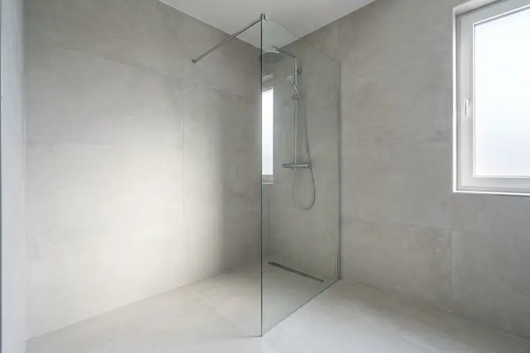 Douche de plain-pied carrelée installée à la place d’une ancienne baignoire, paroi vitrée et siphon de sol